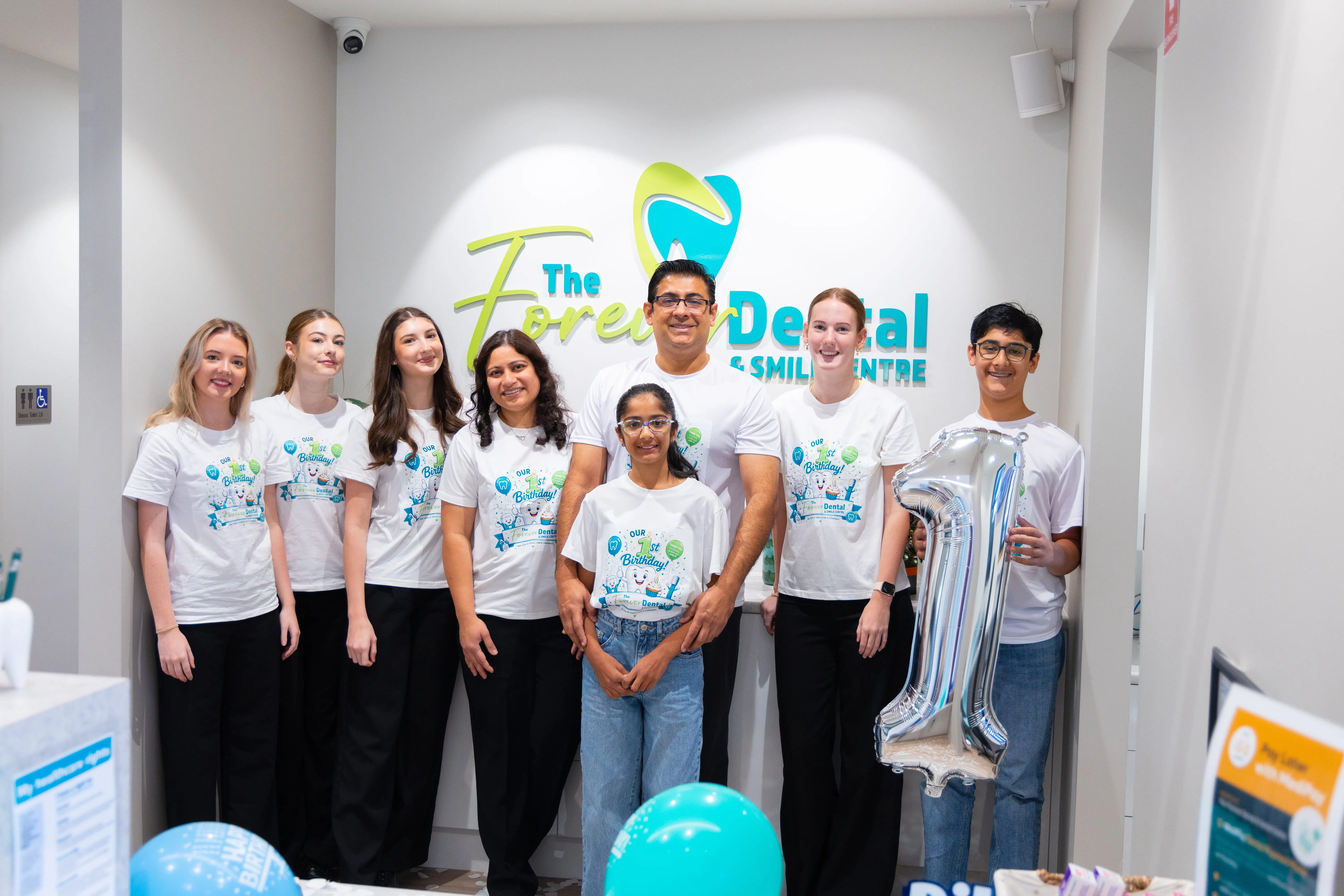The Forever Dental & Smile Centre team celebrating their first anniversary with family members in the Toowoomba dental clinic.