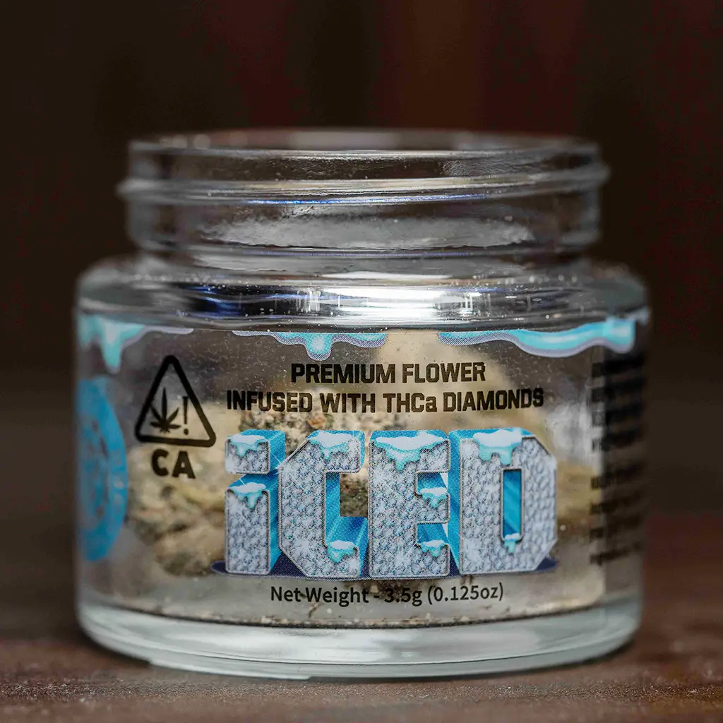 Dense cannabis flower coated in sparkling trichomes inside of a eighth glass jar.