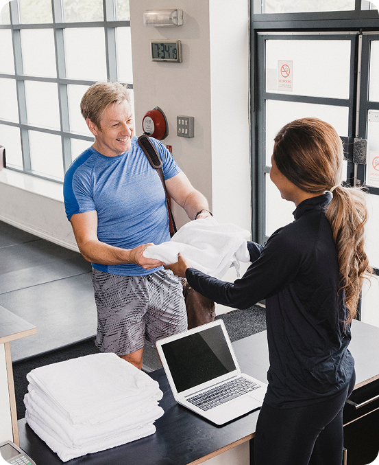 Gym member being handed a towel by happy gym employee