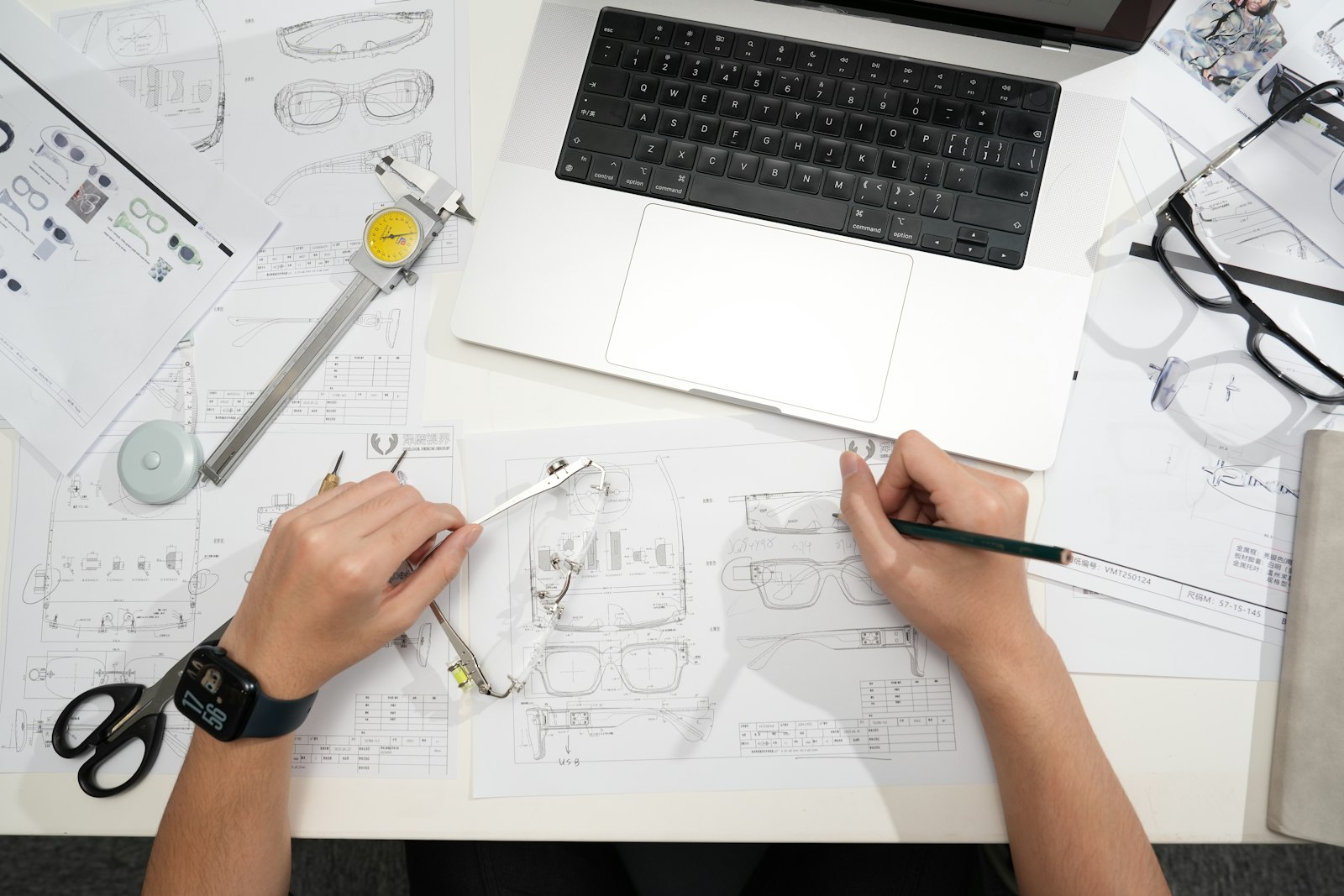Designer sketching product design with laptop and tools