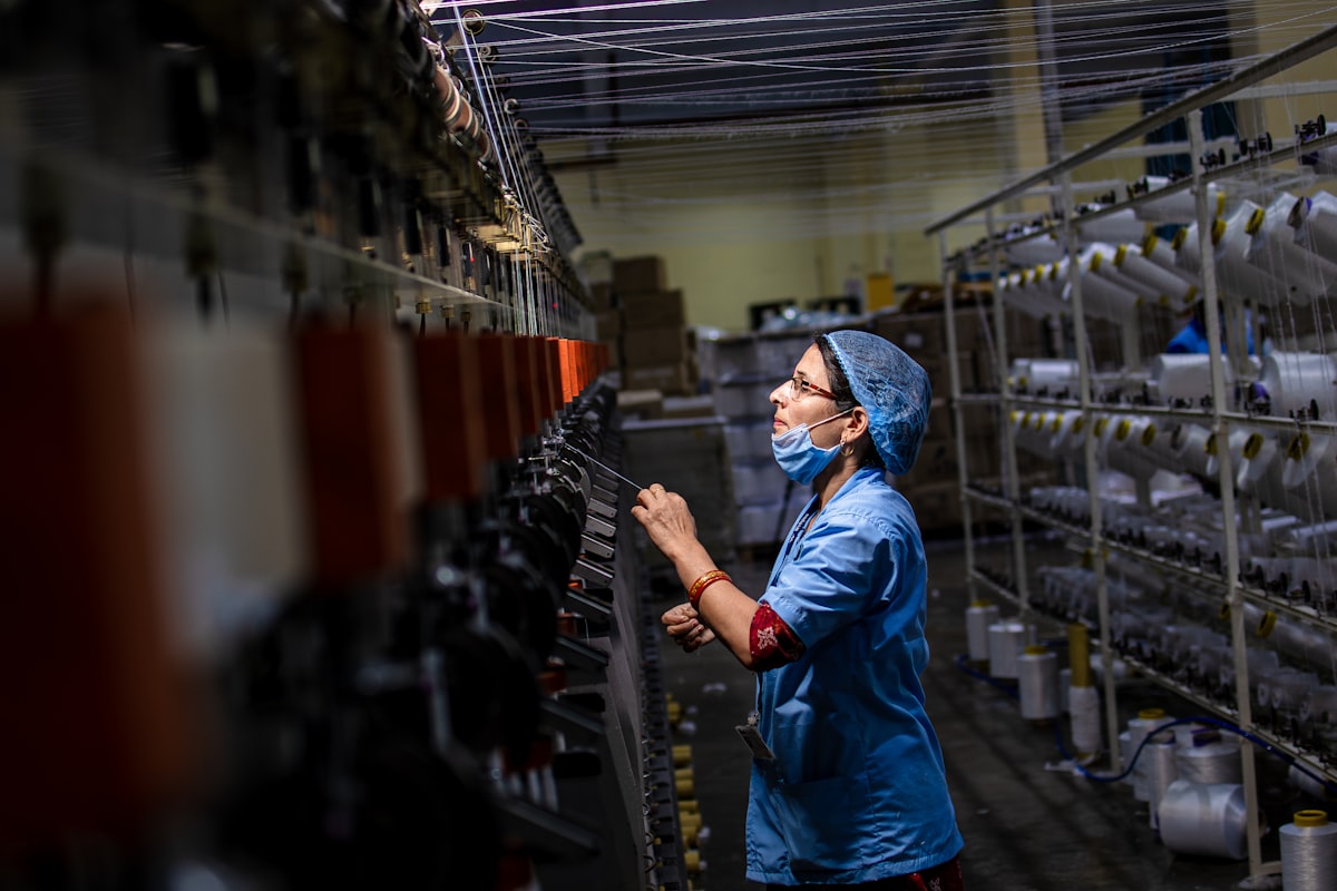Factory worker checking thread compatibility on a machine