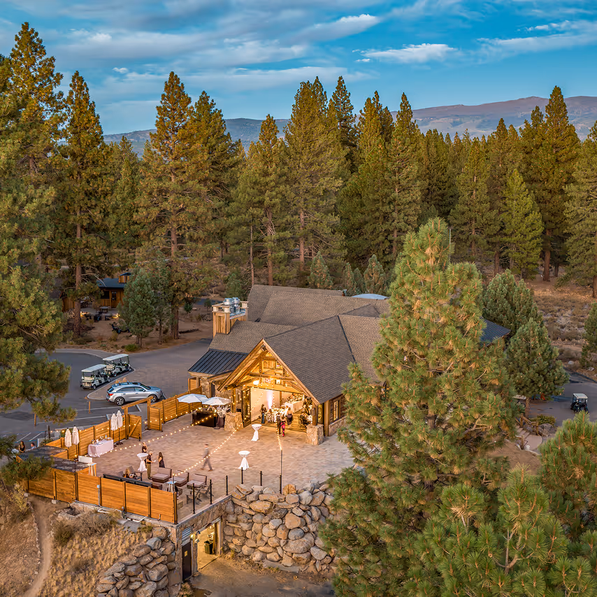 An aerial view of a lodge surrounded by pine trees.