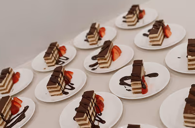 A table topped with white plates filled with desserts.