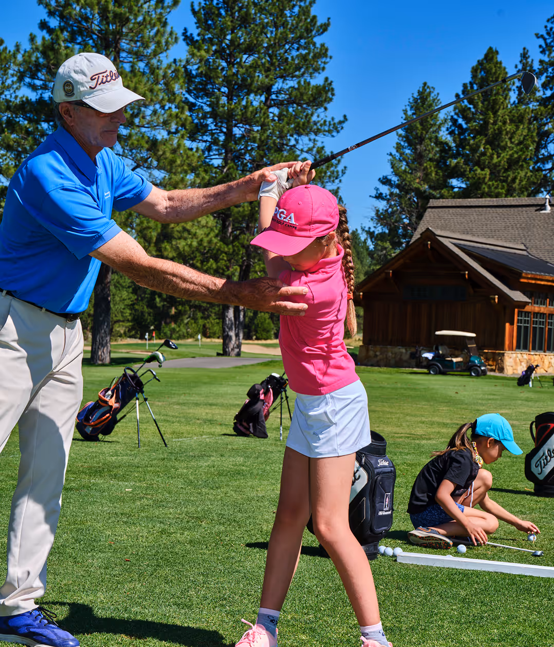 A man teaching a little girl how to swing a golf club.