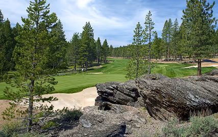 A golf course surrounded by trees and rocks.