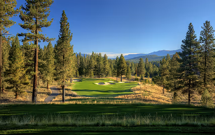 A golf course surrounded by trees and mountains.