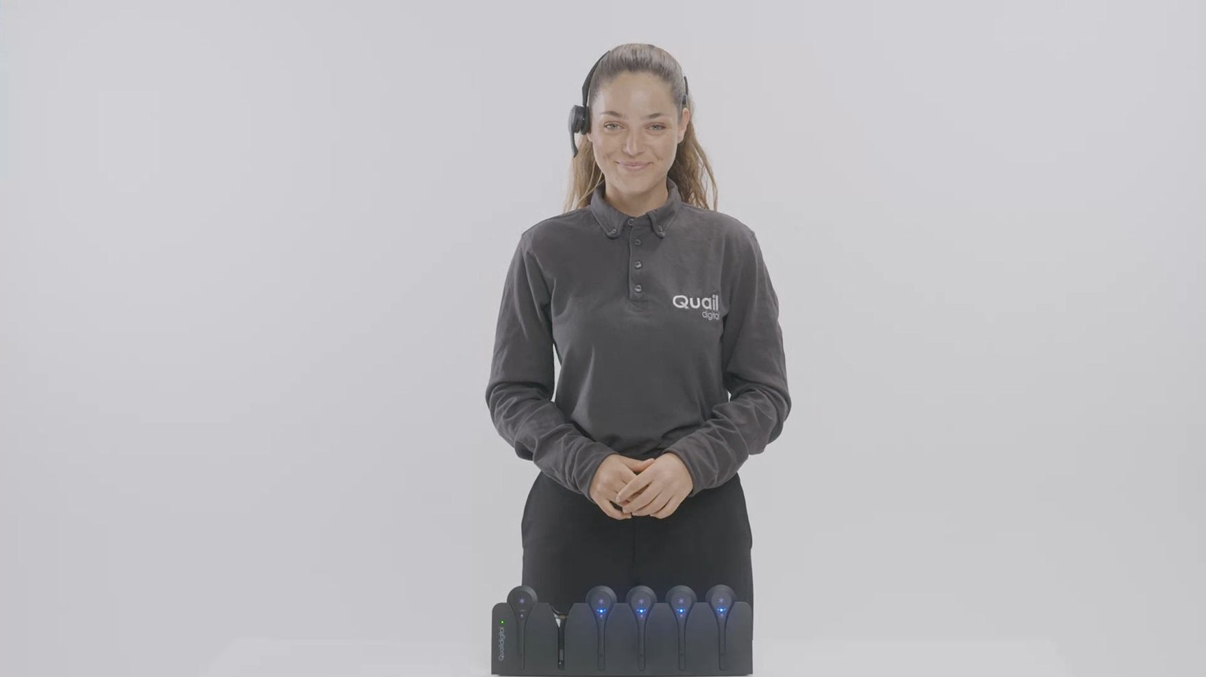 Female wearing Pro12 headset in front of rest of headsets in charger