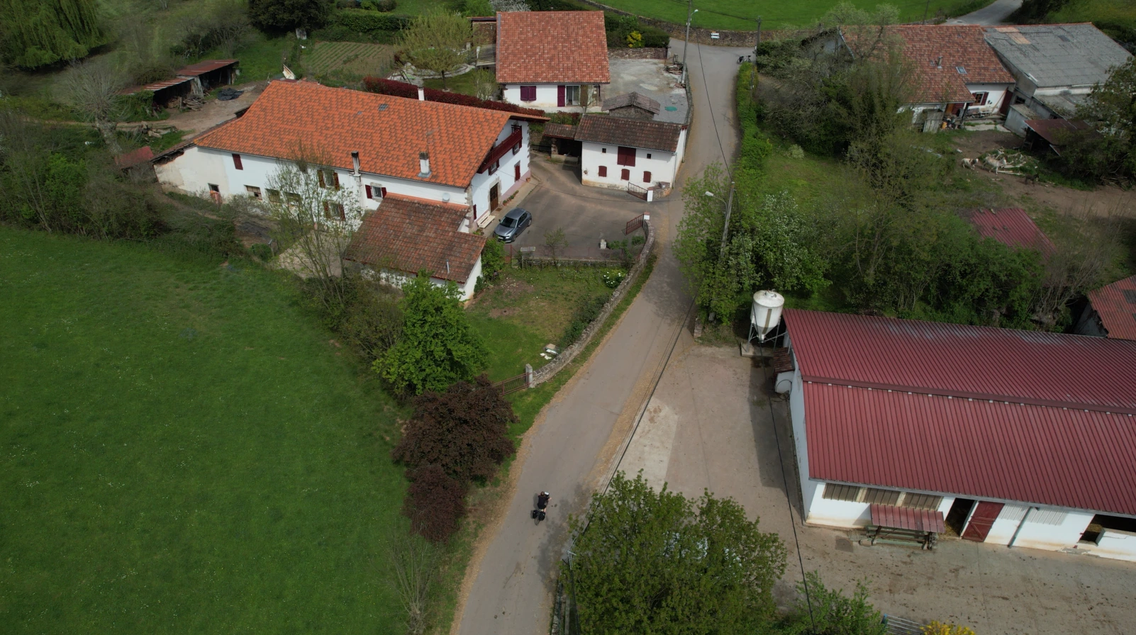 Aerial view of a cyclist on a road between traditional Basque houses with red roofs and a green field.
Turnkey bike holidays from The Family Bike.