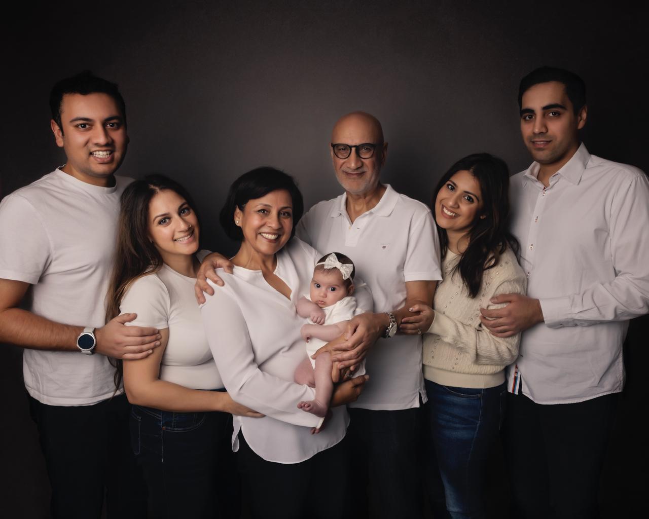 Newborn baby sleeping peacefully on a white blanket with smiling parents gently leaning close.