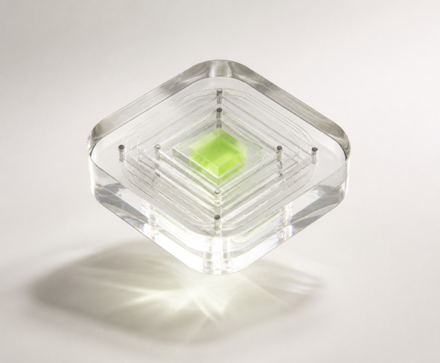 A clear glass cube with a visible green core inside