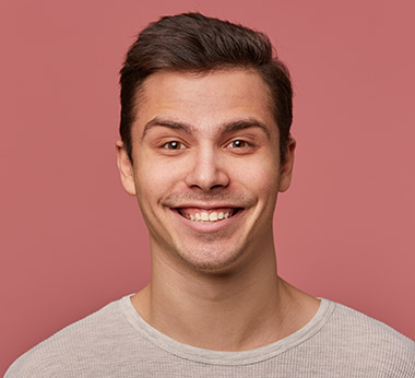 Jonge man met vrolijke glimlach in grijs shirt