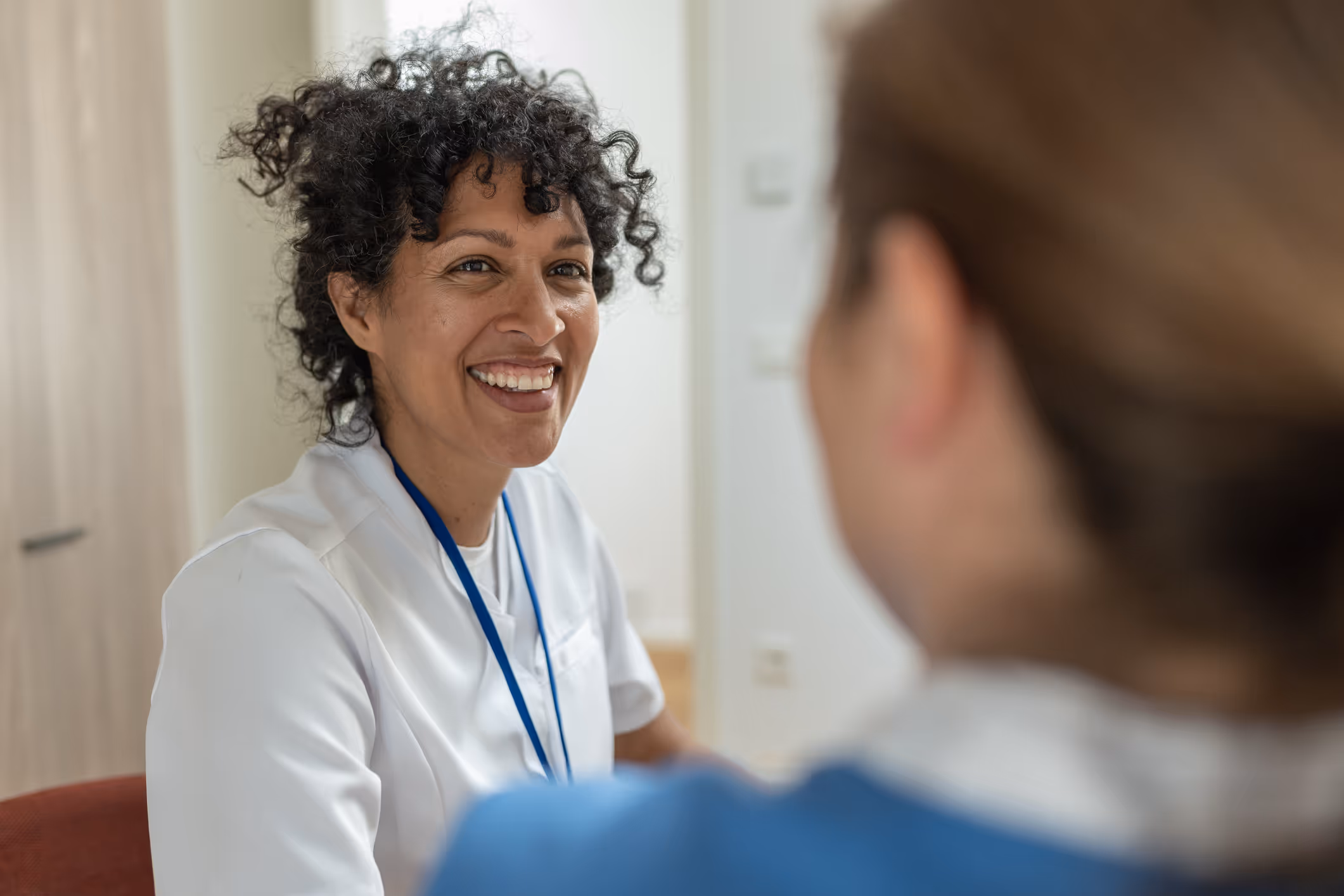 Vriendelijke arts in gesprek met patiënt tijdens medische consultatie in praktijk