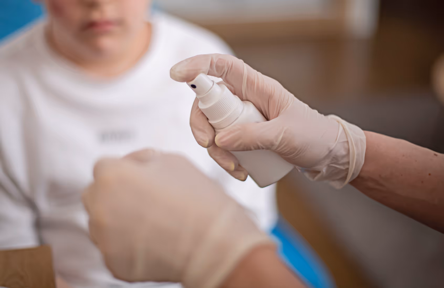 Handen met handschoenen houden wondspray vast