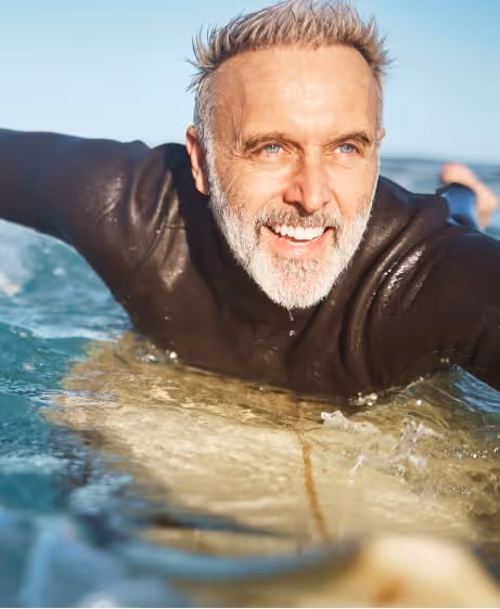 Smiling older man enjoying the ocean, symbolizing the energy and vitality supported by vitamin injections.