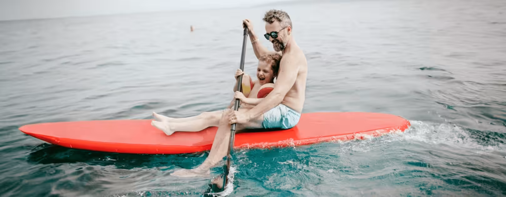 Smiling man kayaking with his child, symbolizing the vitality, wellness, and active lifestyle supported by Gameday Men’s Health vitamin injection therapies.