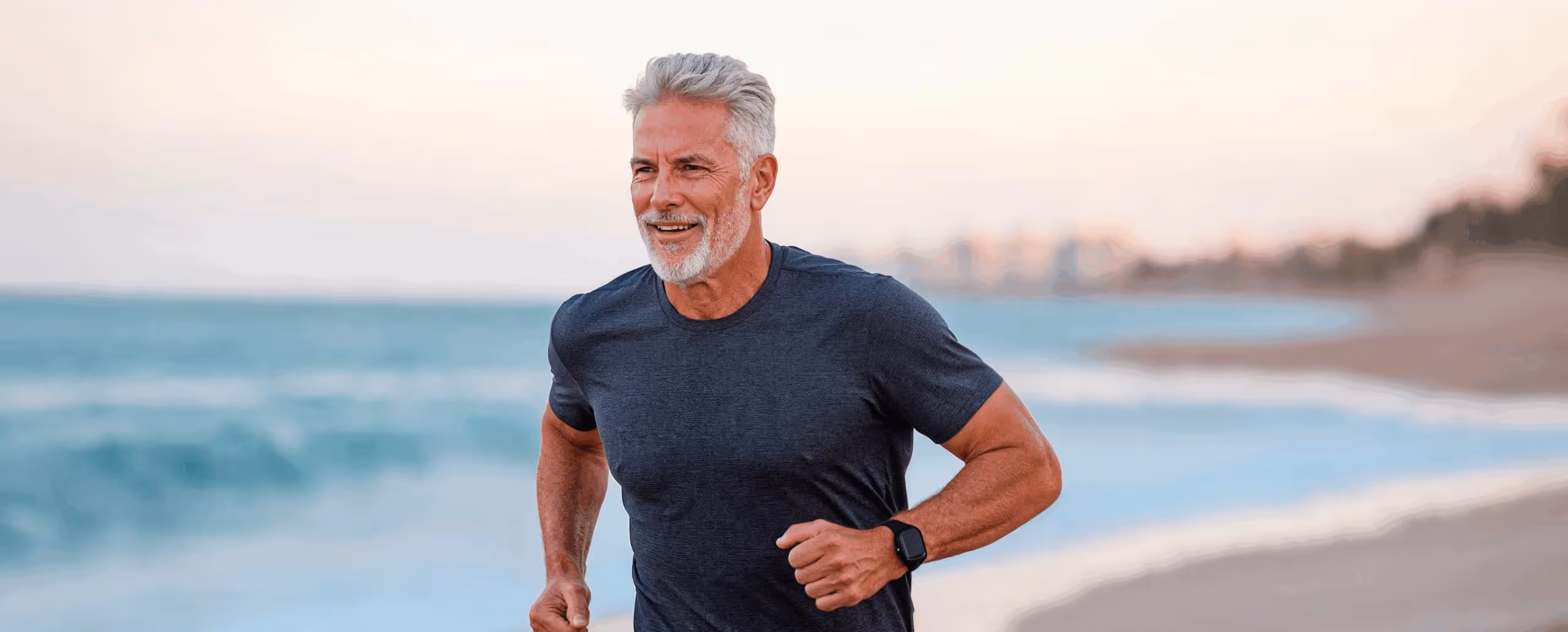 Older man jogging along the beach at sunrise, representing vitality, muscle support, and active aging benefits from Tri Amino Acids.