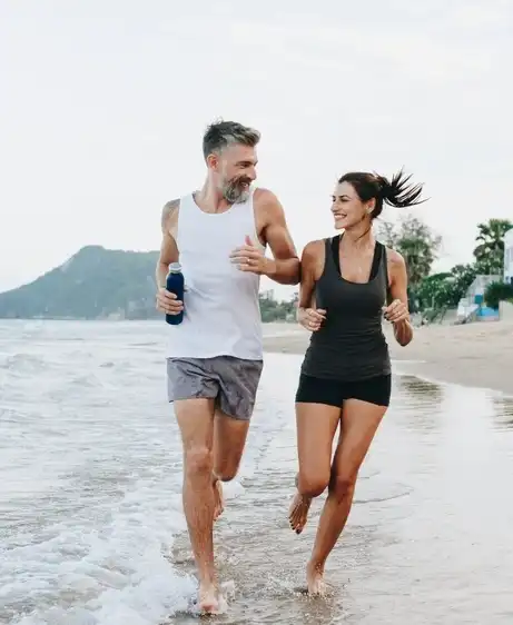 Healthy couple jogging on the beach after MIC B12 vitamin injections, feeling energized and active.