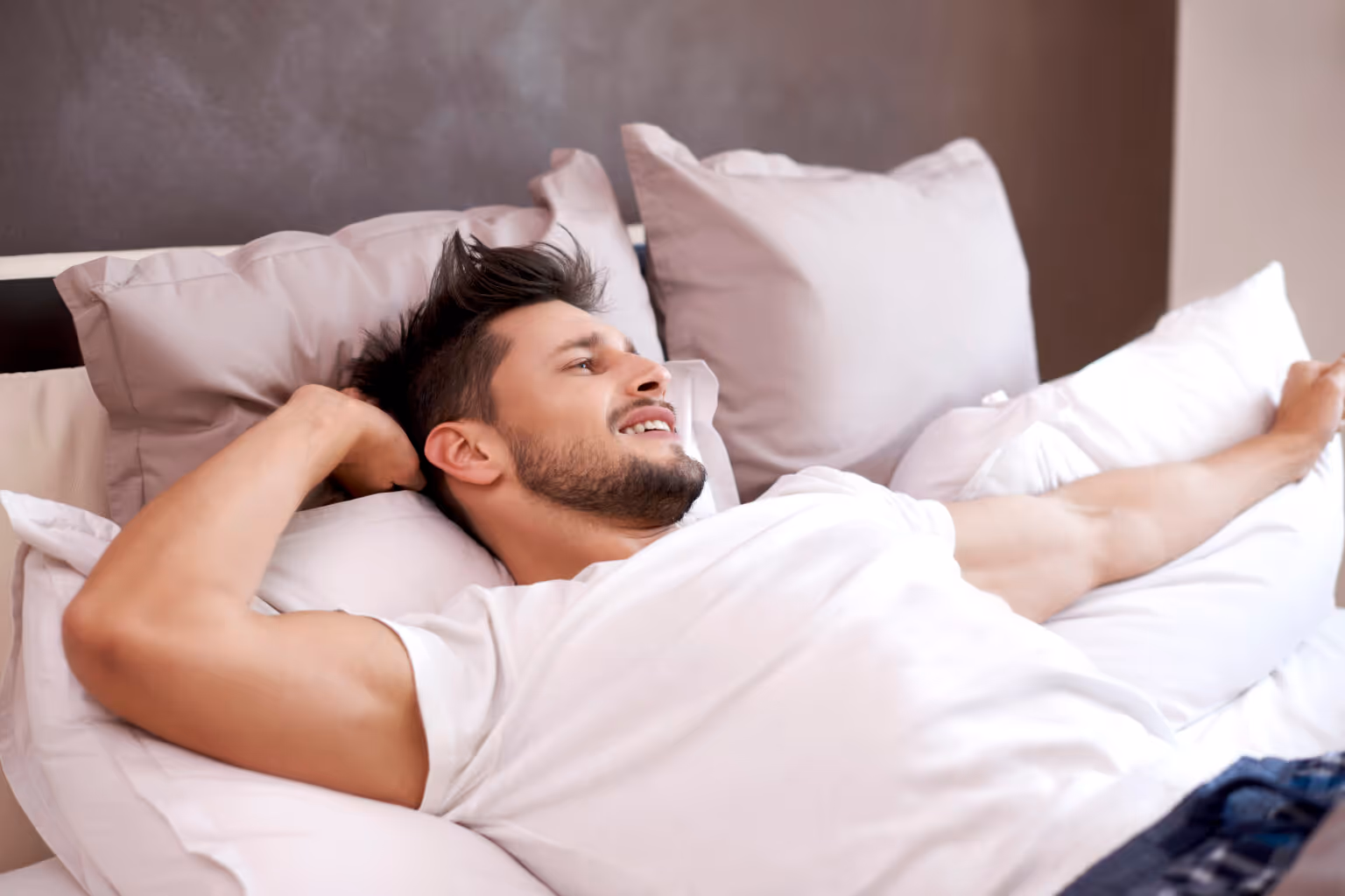 Fit man waking up in a cozy bed, smiling, showing the positive mental connection between mood and weight loss assisted by peptides.