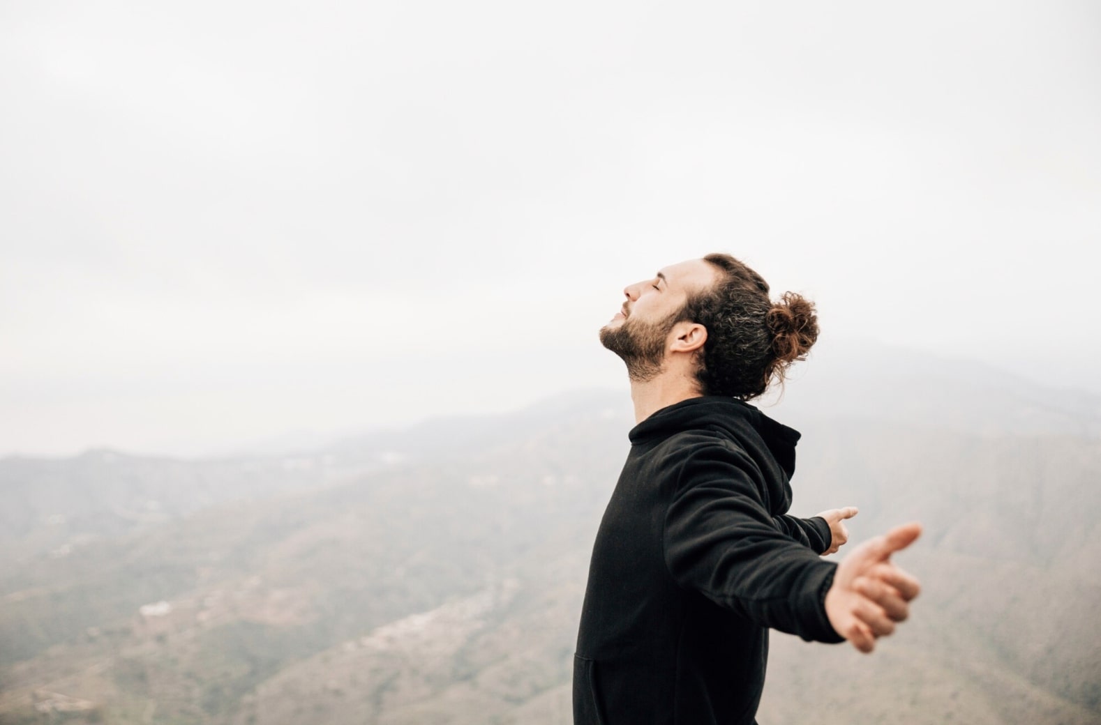 A man happily standing on a mountain peak, symbolizing renewed confidence and a fresh start thanks to effective ED treatment options for 2026.