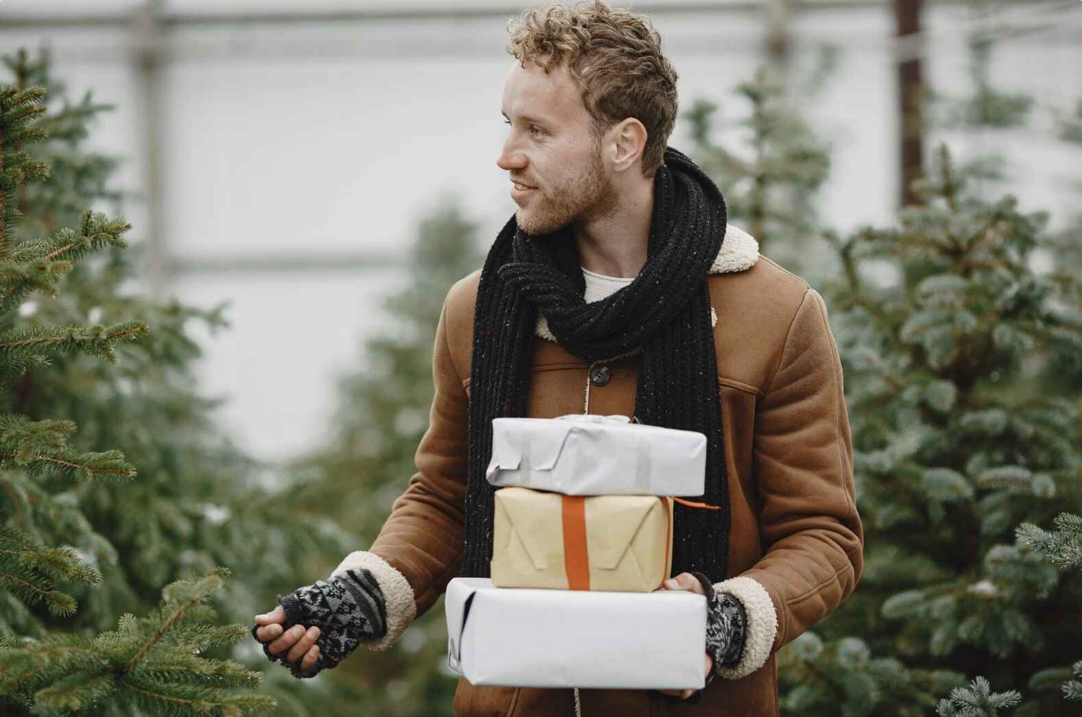 Happy man with beautifully wrapped gift boxes in his hands, showcasing the idea of gifting health, self-care, and wellness to men.