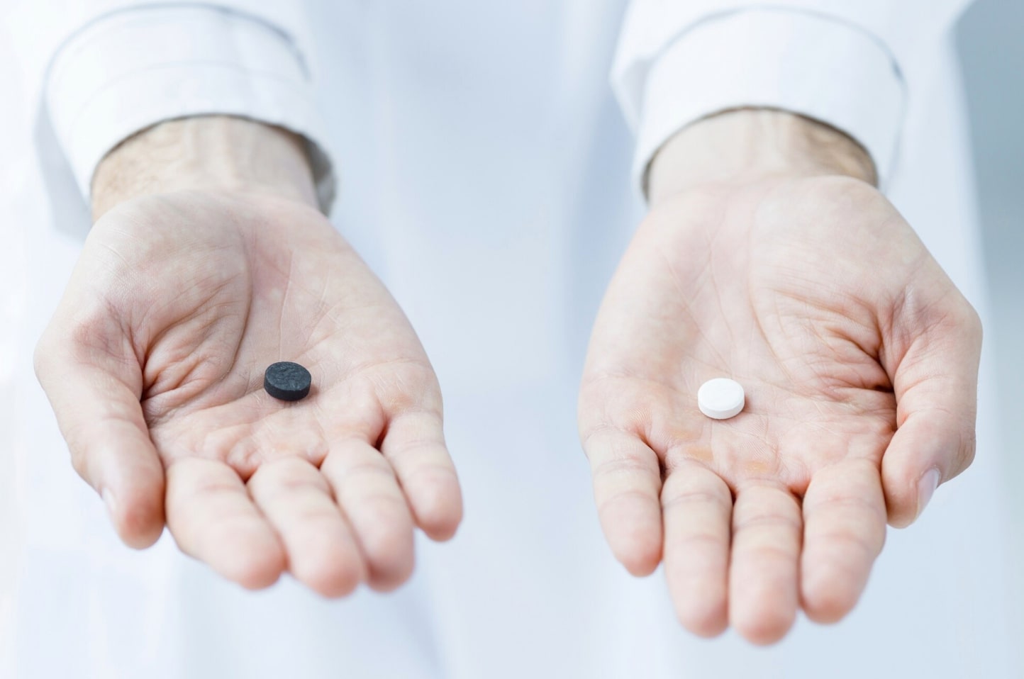 Doctor holding two different pills in each hand, clearly displaying Viagra and Cialis to illustrate the comparison between the two erectile dysfunction medications.