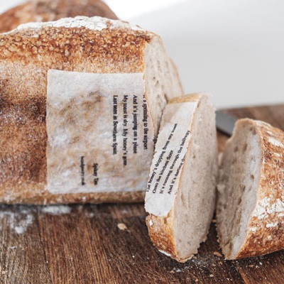 A loaf of sourdough with a wafer oaoer poem baked into the bread crust.