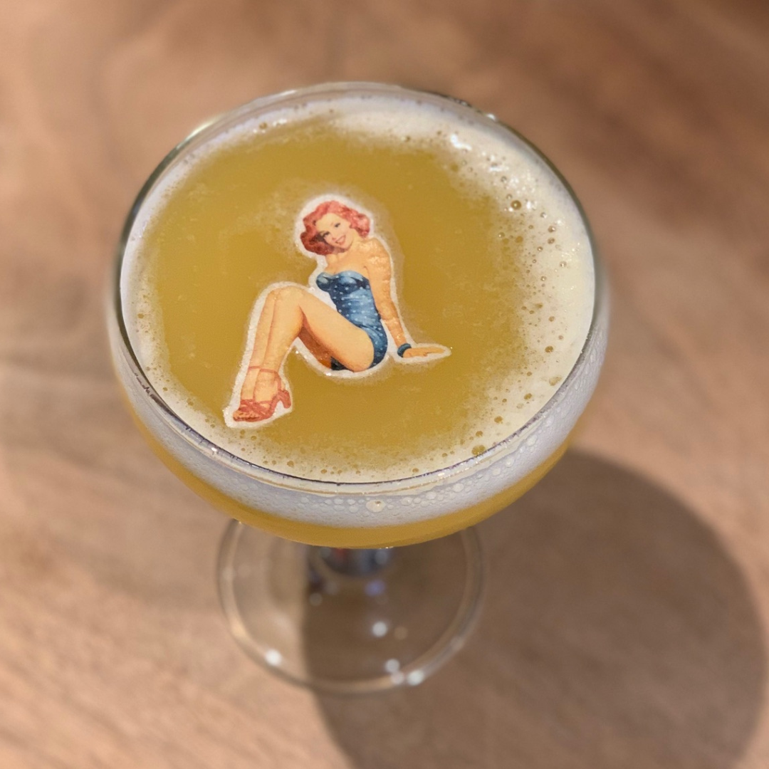 A cocktail with a custom shaped  topper of a vintage pin-up girl.
