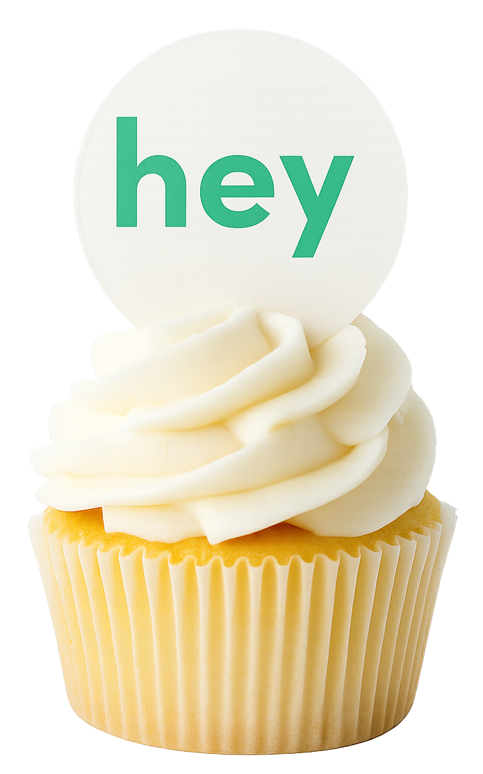 Cupcake with a round wafer cupcake topper sticking out of it that has the wod 'hey' printed on it.