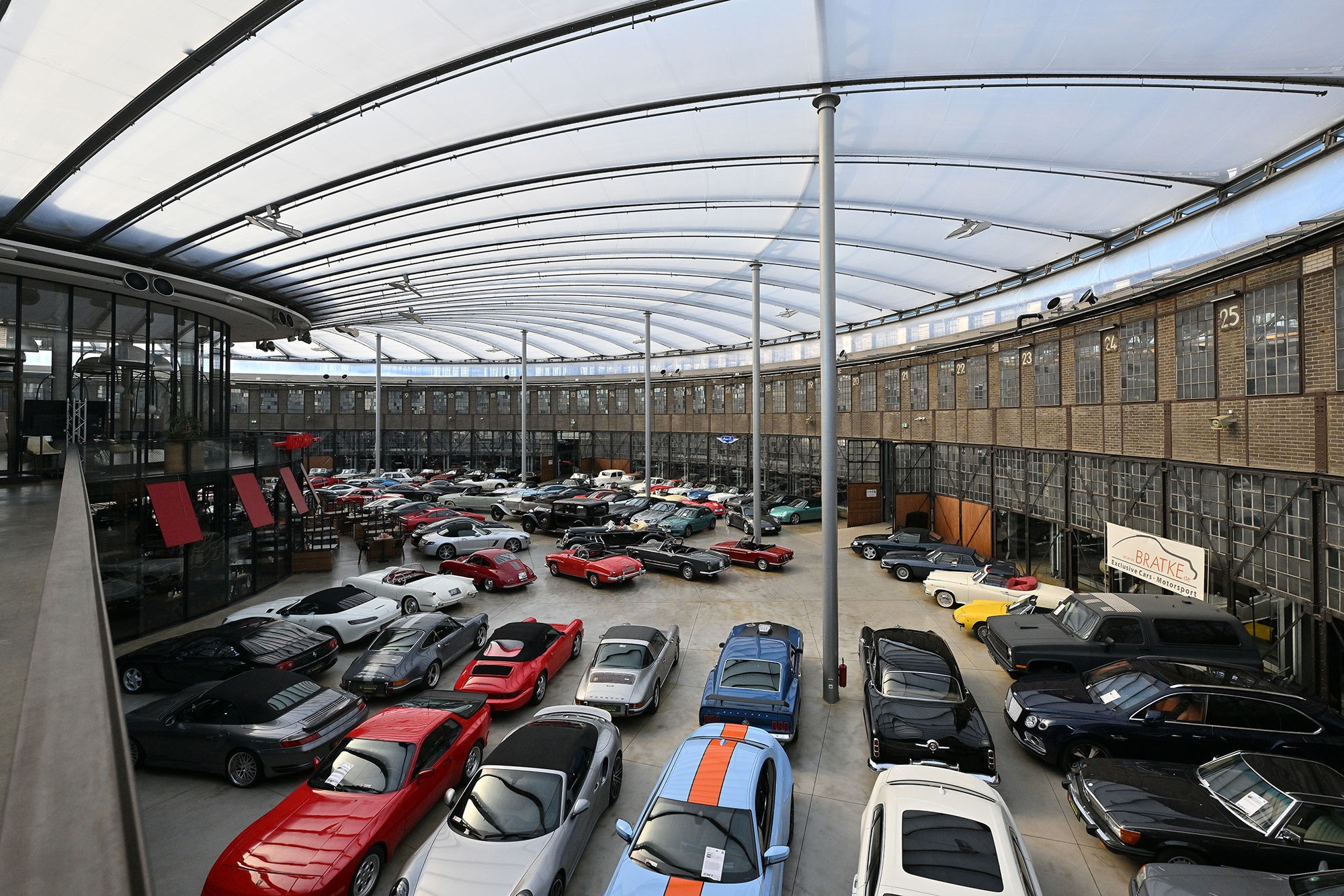 Große Halle, in der mehrere Fahrzeuge und Oldtimer stehen.