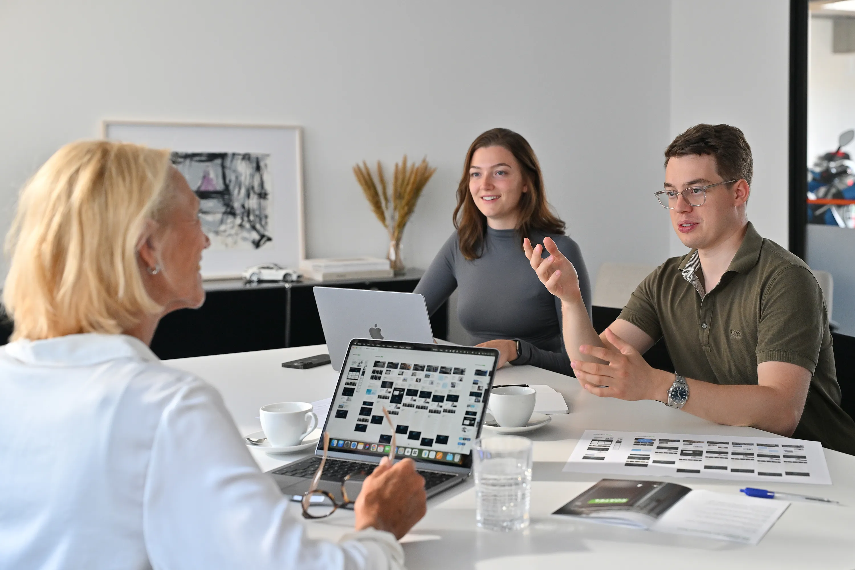 Drei Personen, die an einem Schreibtisch sitzen und sich unterhalten