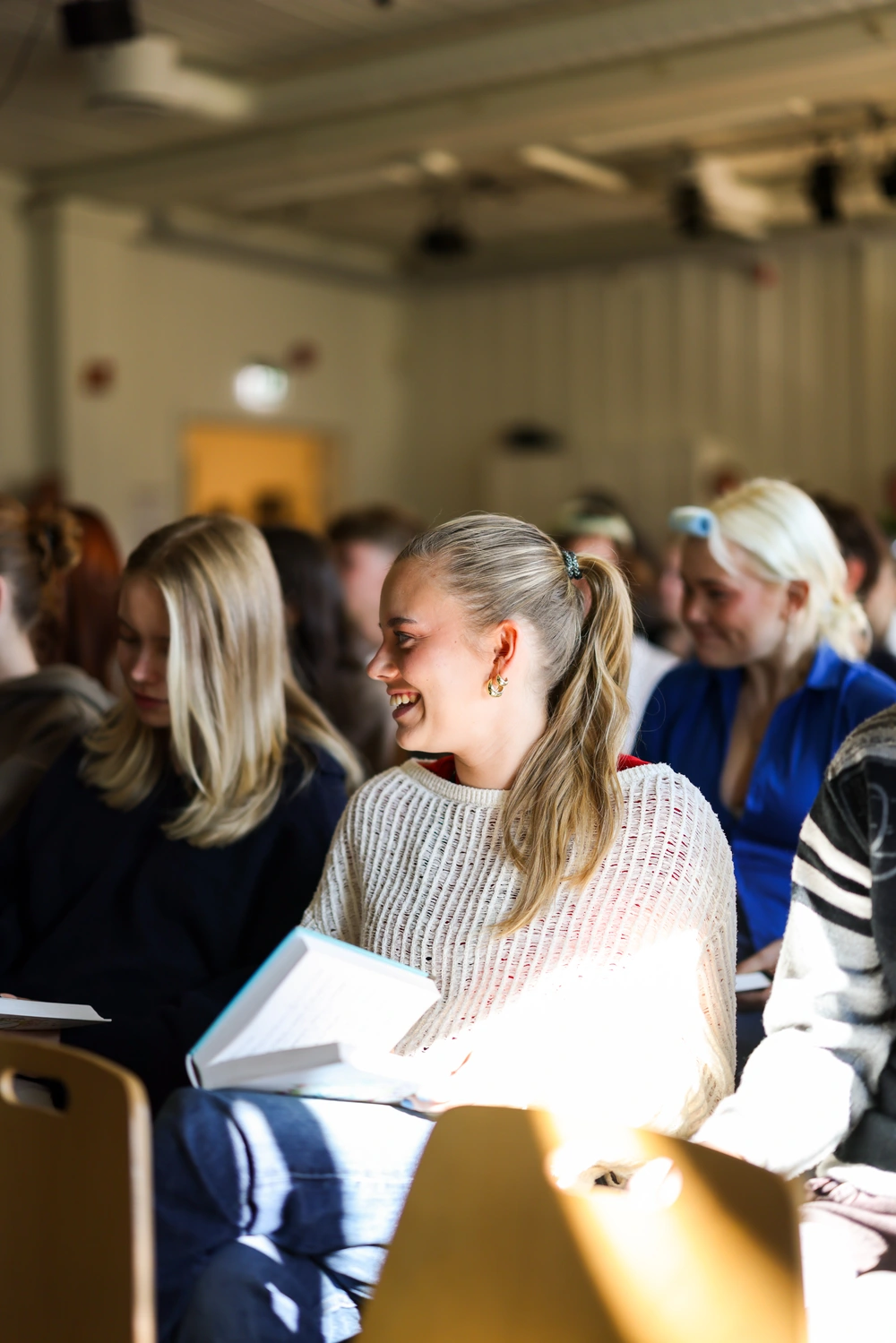 Elever ved Ringerike Folkehøgskole sitter sammen og synger under morgensamling, et bilde som viser engasjement og sosialt fellesskap på skolen.
