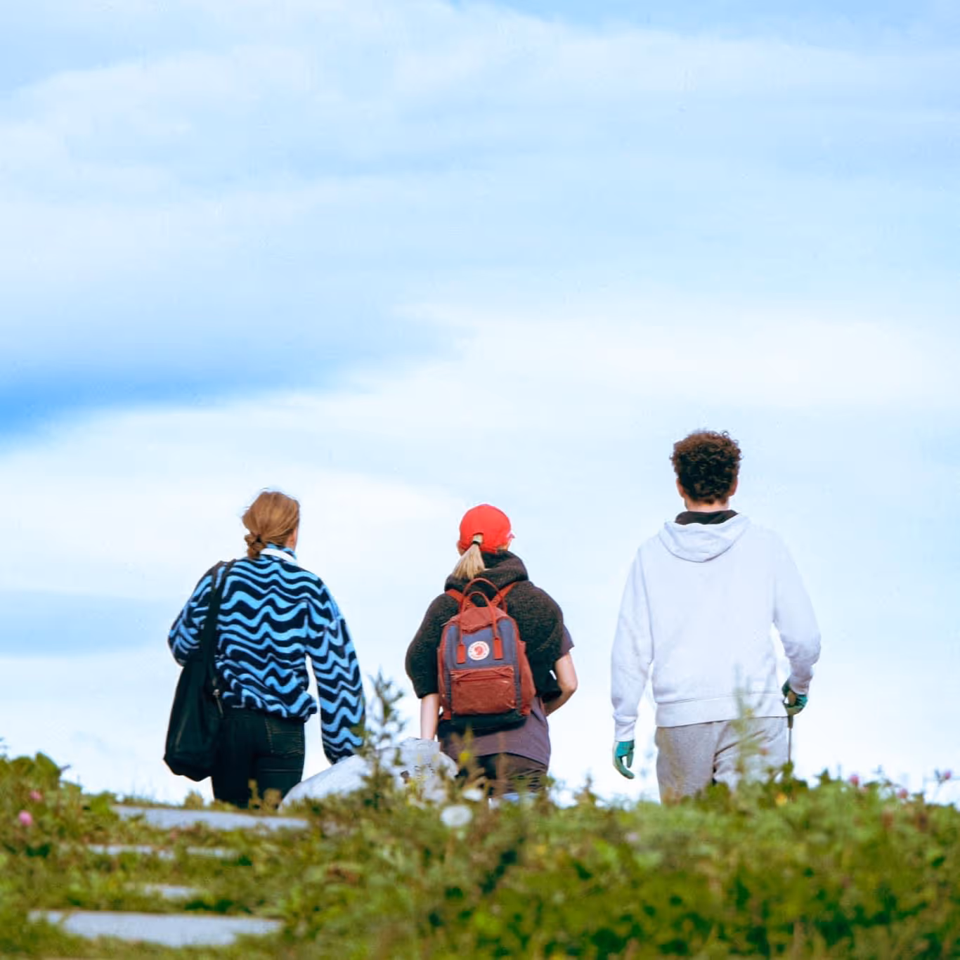 Elever fra linjen UT på Ringerike Folkehøgskole går sammen på fjelltur under blå himmel, et bilde som viser friluftsliv, samarbeid og naturopplevelse.