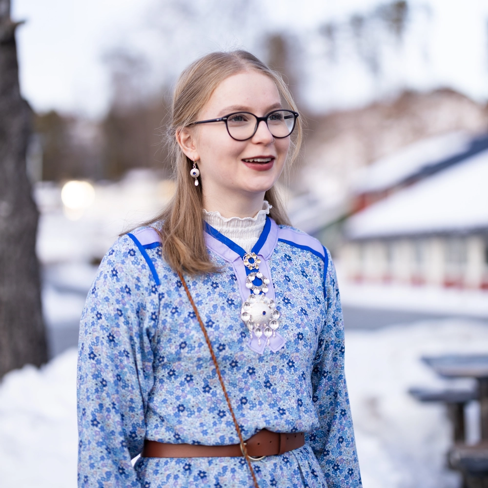 Elev fra Ringerike Folkehøgskole smiler i samebunad ute i vinterlandskap, et bilde som viser samisk tradisjon og glede på folkehøgskole.