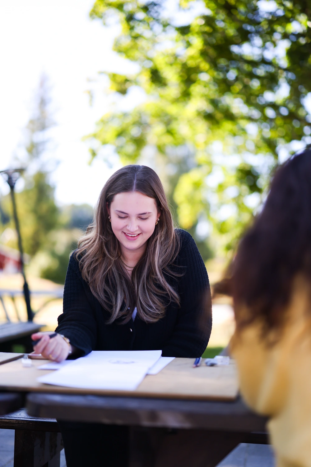 Elev ved Ringerike Folkehøgskole tegner utendørs i solskinn, som en del av skolens kreative undervisning i kunst og design.