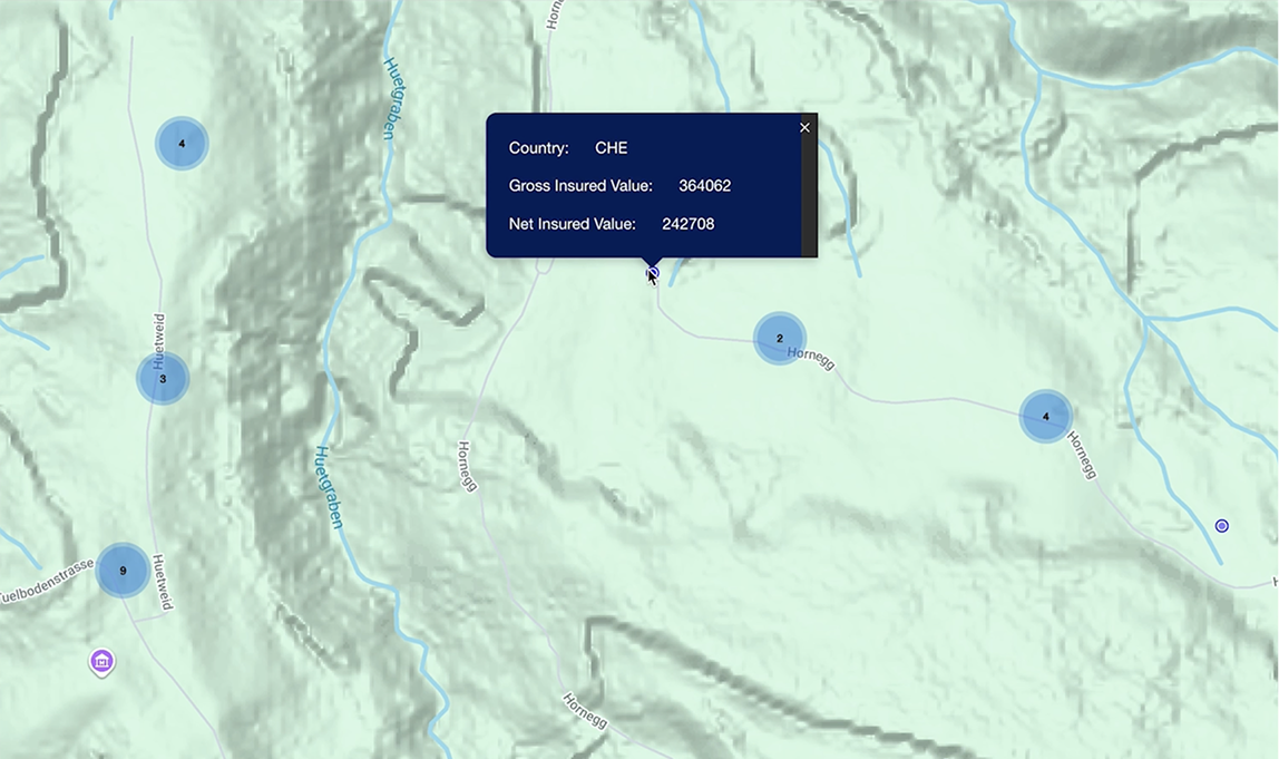 A topographic GIS map interface showing blue circular data points with a pop-up window displaying specific gross and net insured values for a selected location. The analysis is performed in Graph by Quarticle. 