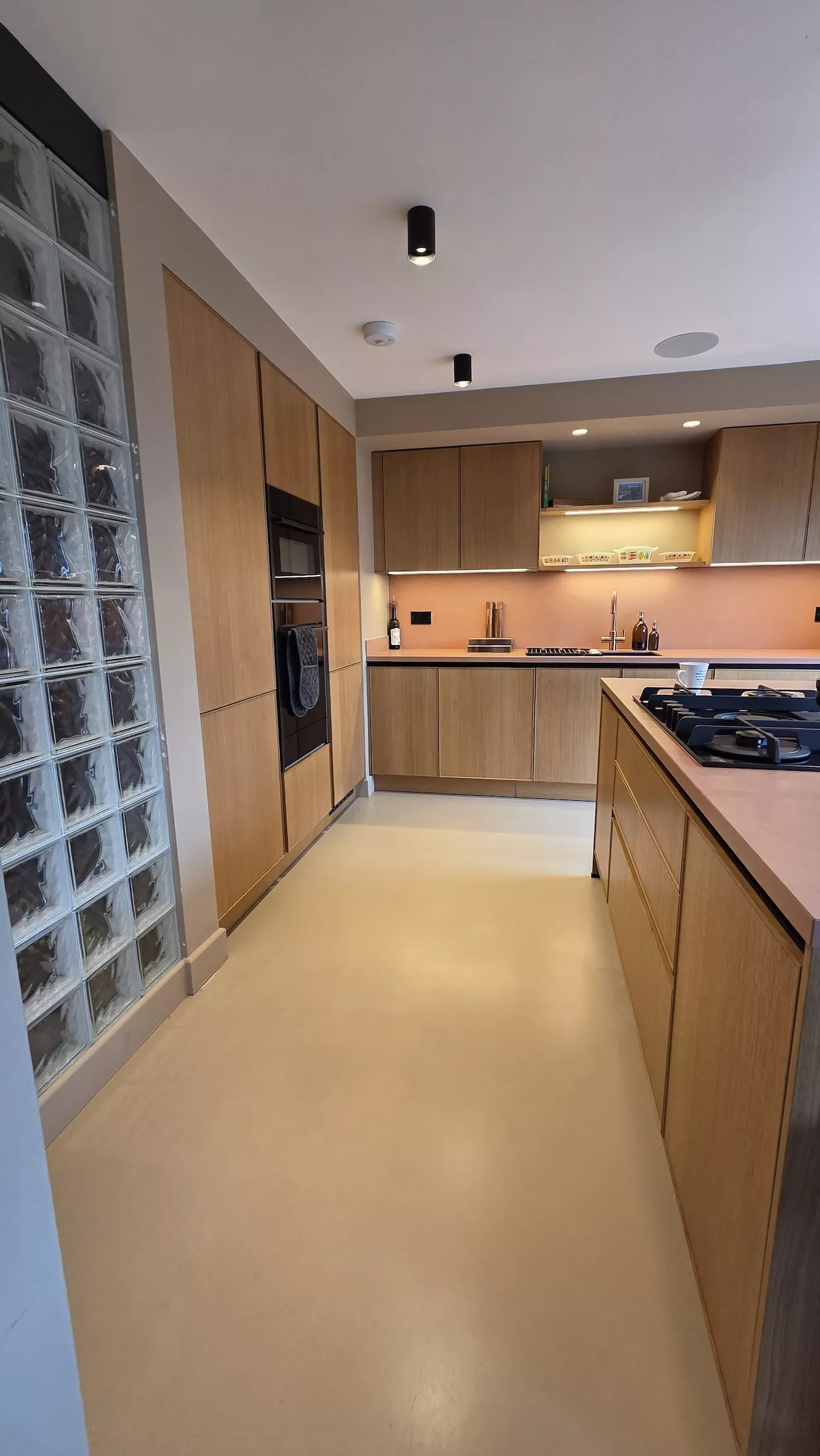 Polished concrete overlay kitchen floor with warm wood cabinets and seamless concrete overlay finish