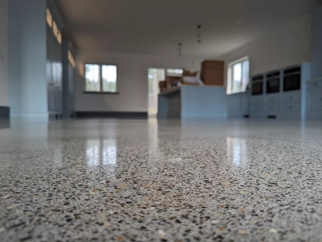 Residential polished concrete overlay floor in an open-plan kitchen extension showing full aggregate exposure and high-gloss finish
