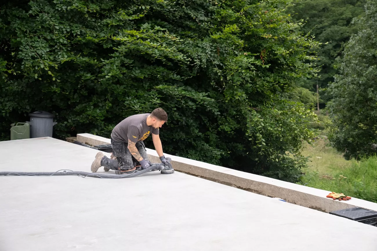 Specialist hand-grinding the edge of a polished concrete floor with dust extraction during installation