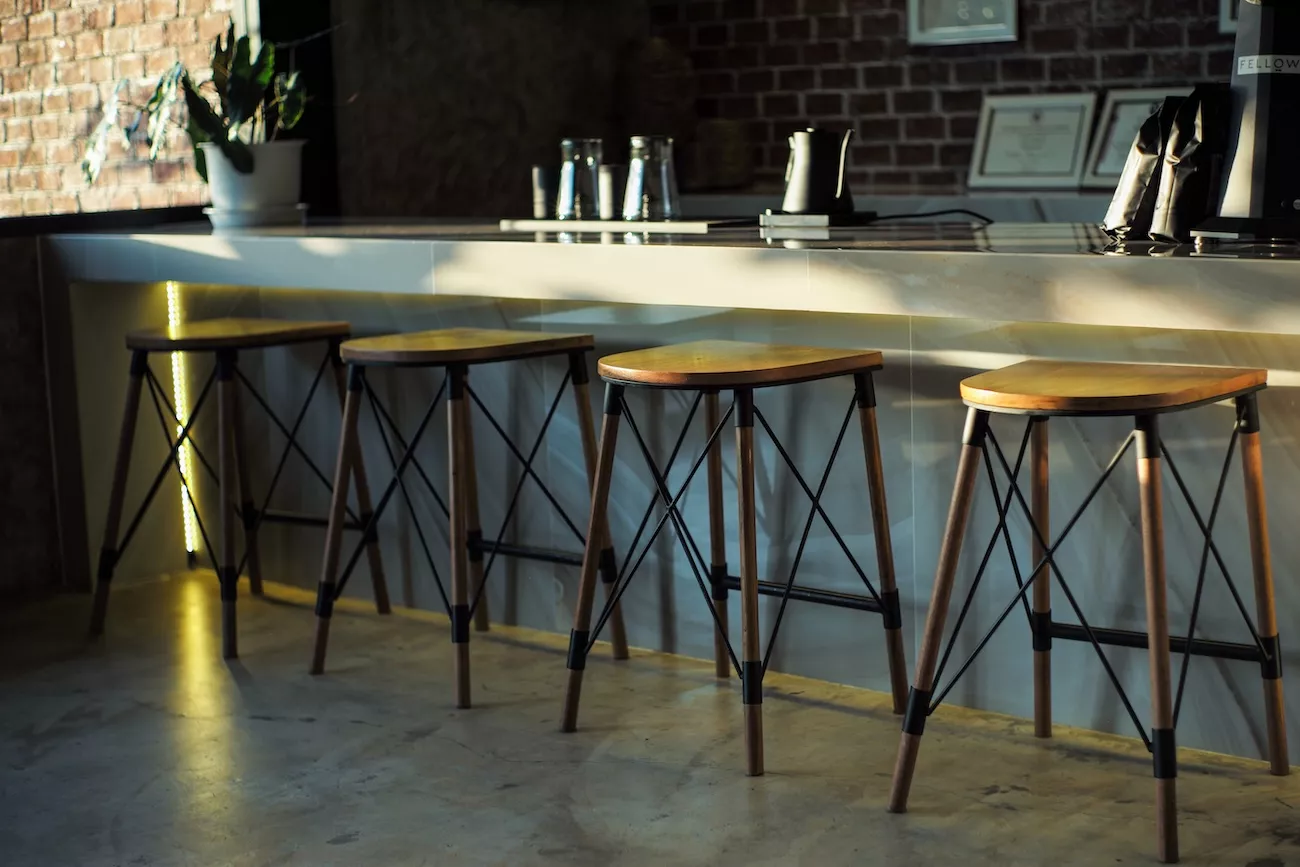 Polished concrete floor beneath a row of bar stools at a hospitality venue counter with exposed brick wall