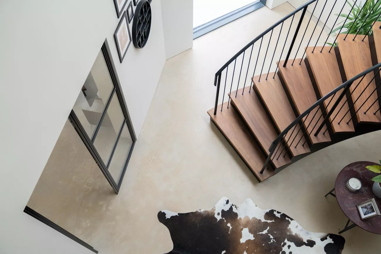 Beige polished concrete floor in a Liverpool home with curved wooden staircase