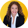 Smiling woman with curly hair in a navy blazer and white blouse on yellow background.