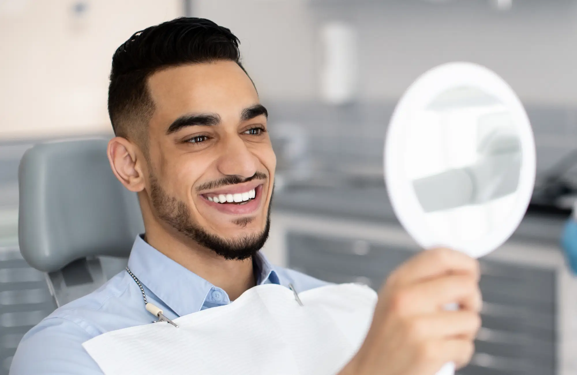 Happy patient looking at teeth whiting results at Kenner Dental Company