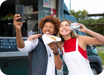 Free Happy multiethnic friends with burgers taking selfie near food truck Stock Photo