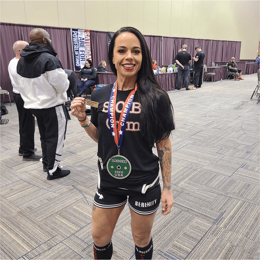 Stacey Heckman, co-owner of S.O.B. Gym, holding a first-place award at a UPA powerlifting meet
