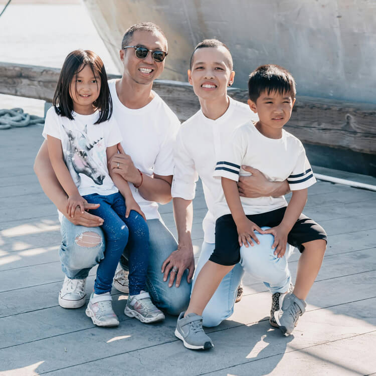 Une famille avec deux papas et deux enfants pose devant un bateau