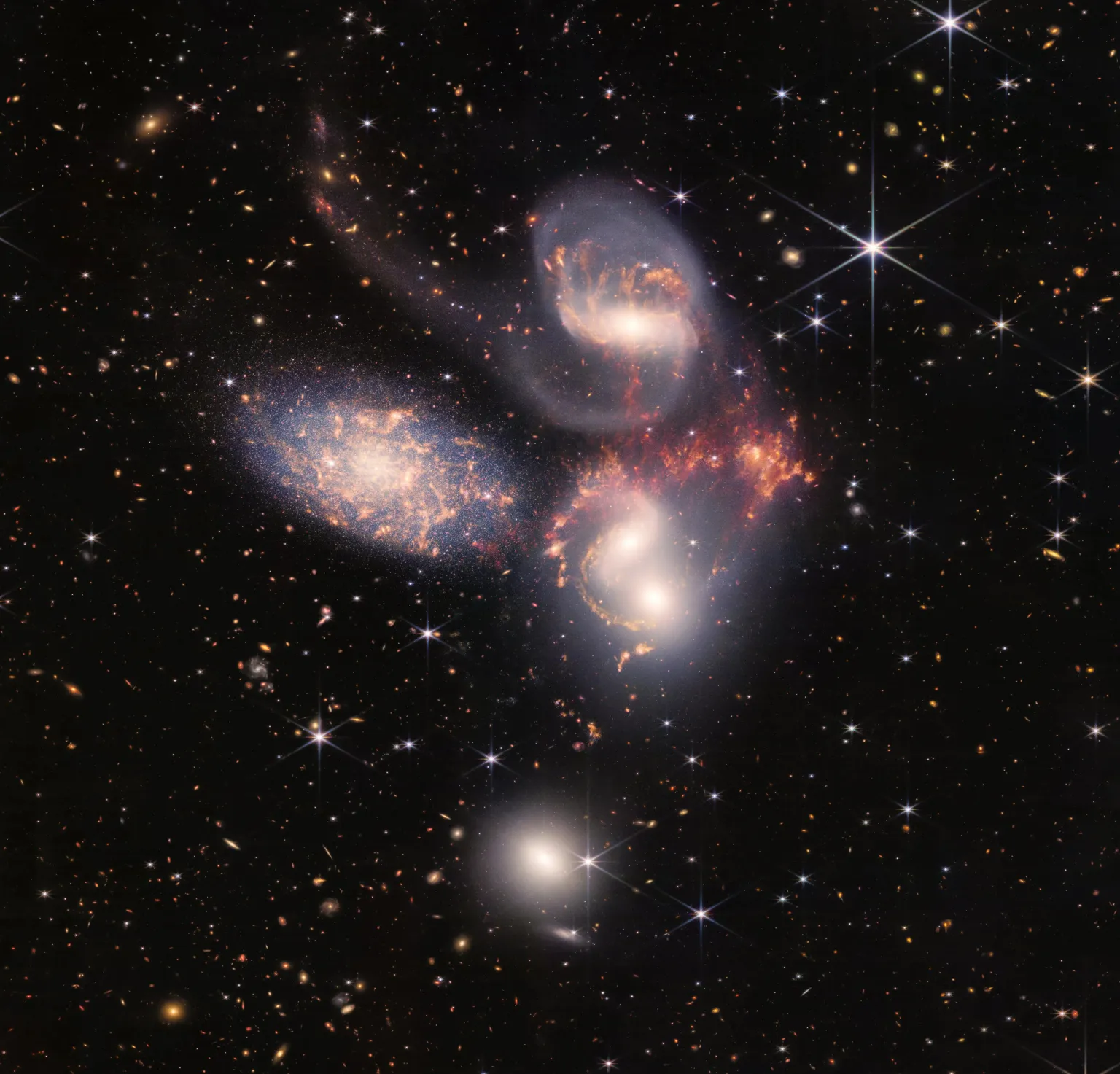 Colorful image of five interacting galaxies with bright cores and surrounding stars in deep space.