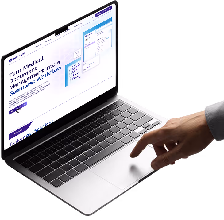 A hand with an extended index finger hovers above on the trackpad of an open laptop with the KAboodle website on the screen.