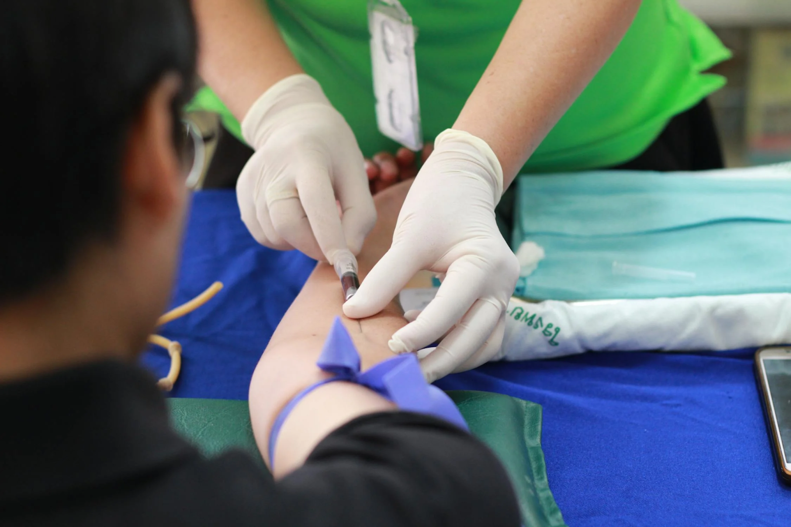 A healthcare worker draws blood from a patient’s arm.