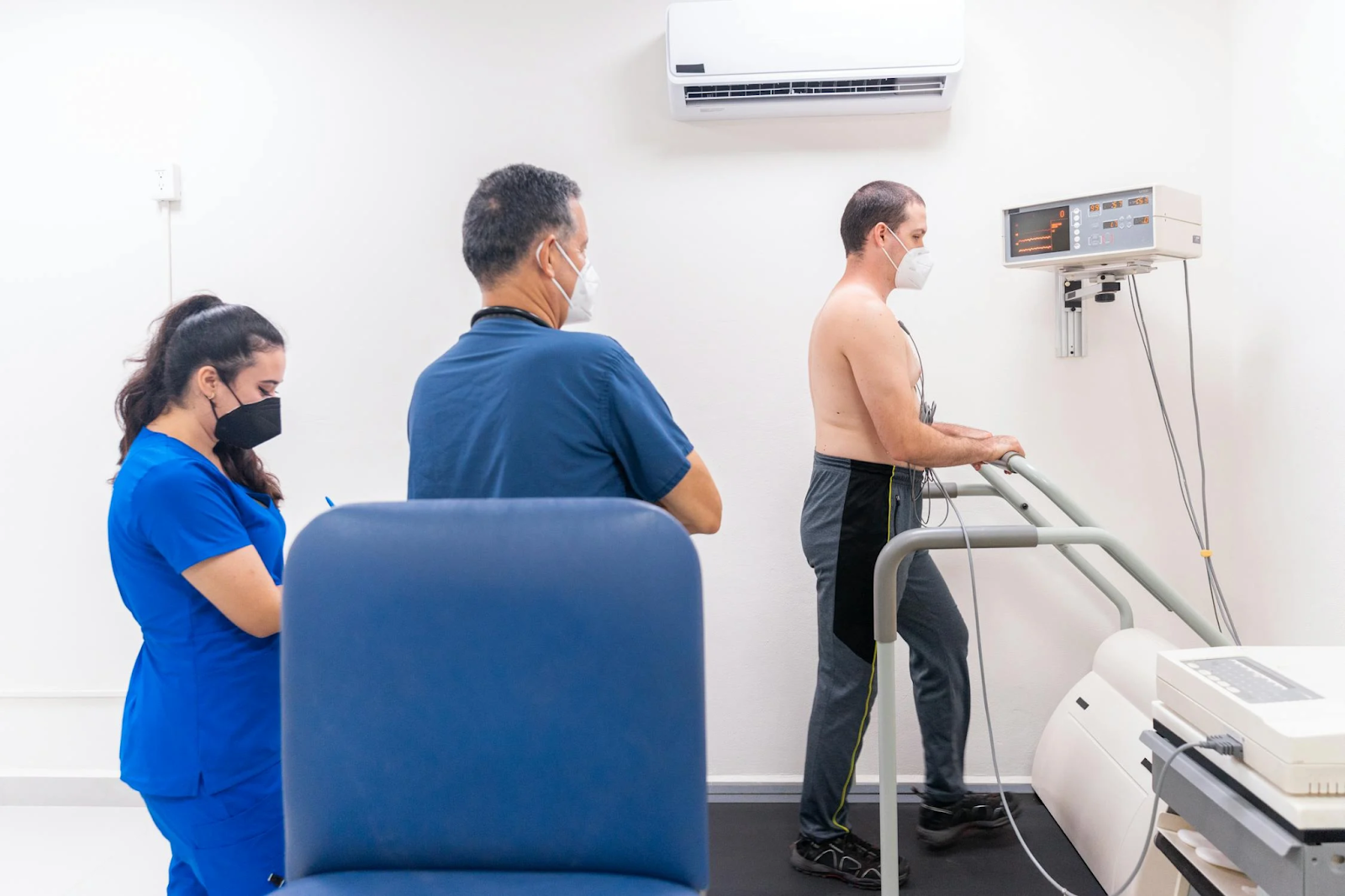 A cardiologist observing a patient during a treadmill-based stress test.