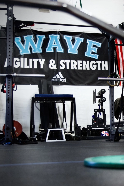A gym interior featuring a sign that reads "Wave Strength and Power" at Volley Strong Inc in Del Mar, CA.